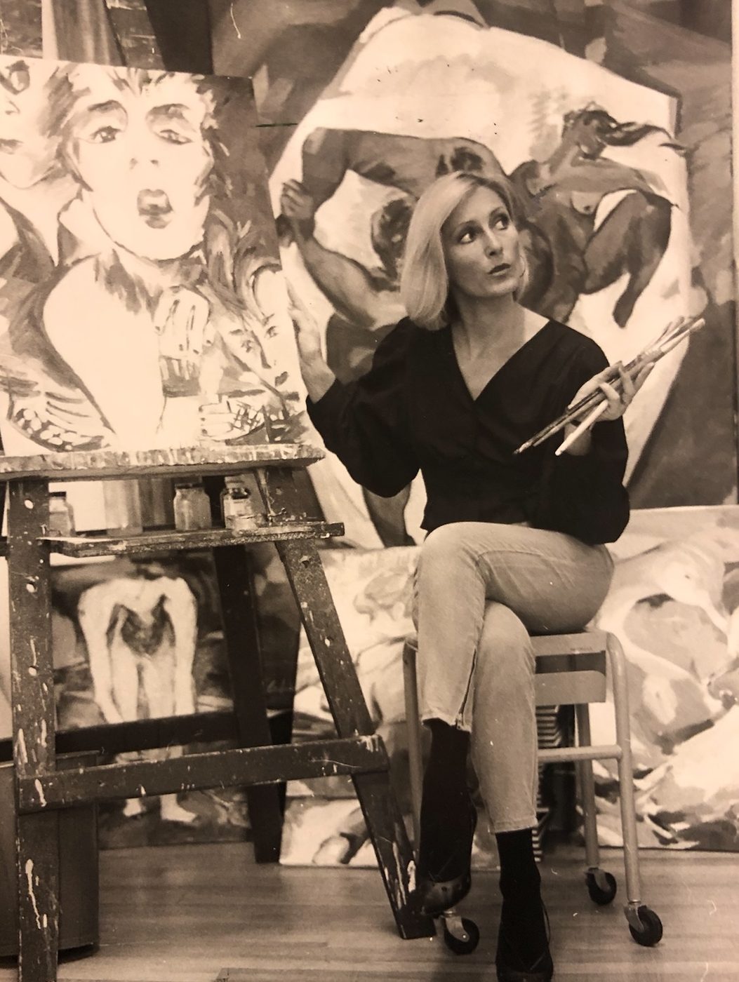 Colette Hébert in her Montreal studio, brushes in hand, surrounded by large figurative canvases