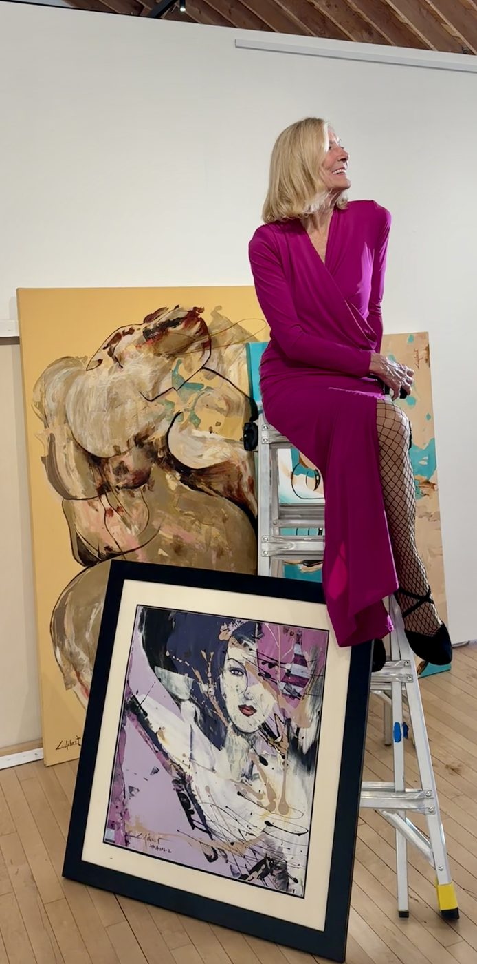 Colette Hébert today, seated on a ladder among her paintings at Union Hall Gallery