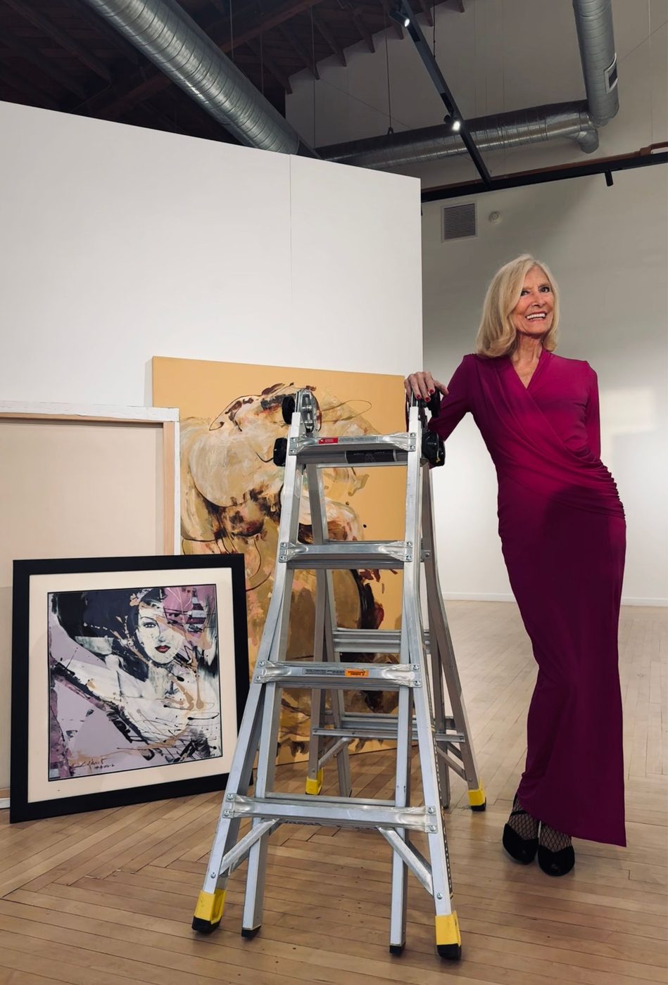 Colette Hébert seated among her paintings at Union Hall Gallery, San Diego